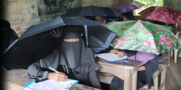 গলাচিপায় বাম হাতে ছাতা ডান হাতে কলম নিয়ে পরীক্ষা দিচ্ছে শিক্ষার্থীরা